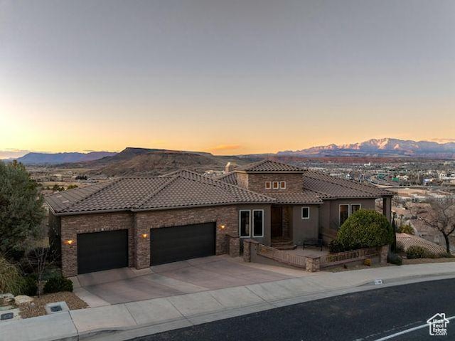 mediterranean / spanish-style house with a garage, driveway, a mountain view, and a tiled roof