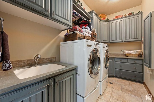 laundry room featuring washer and clothes dryer, stone tile flooring, a sink, and cabinet space