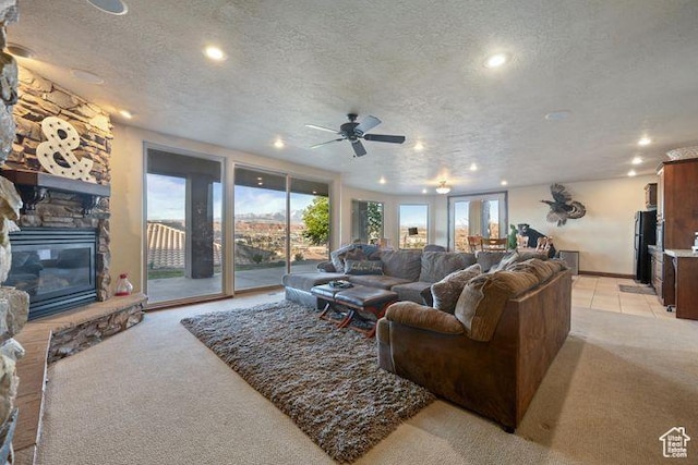 living area featuring a healthy amount of sunlight, light colored carpet, a fireplace, and a textured ceiling