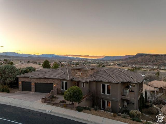 mediterranean / spanish-style house with a tile roof, stucco siding, concrete driveway, a mountain view, and a garage