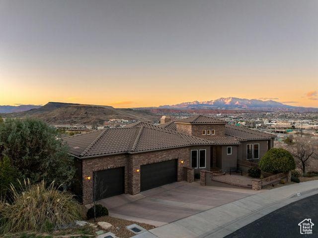 mediterranean / spanish home with a garage, a tile roof, a mountain view, and concrete driveway