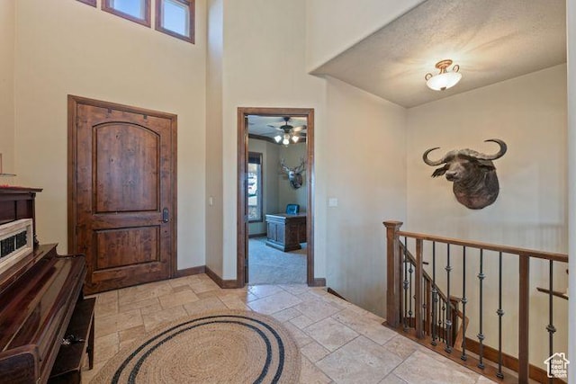 entryway featuring a high ceiling, baseboards, and stone tile flooring