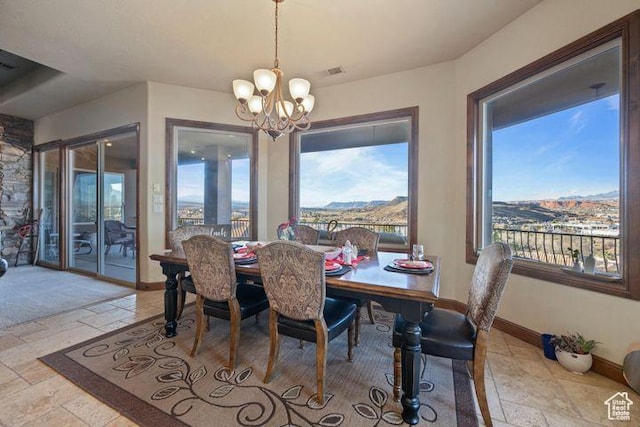 dining space featuring a chandelier, a mountain view, visible vents, baseboards, and stone tile flooring