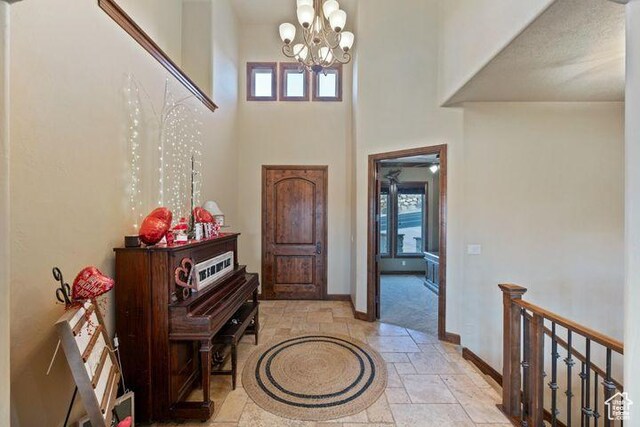 foyer with a high ceiling, baseboards, a notable chandelier, and stone tile floors