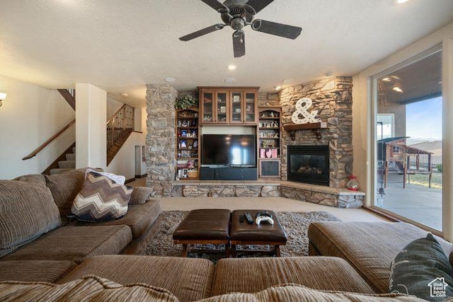 living room with stairs, a textured ceiling, a fireplace, and a ceiling fan