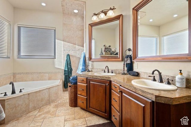 bathroom with double vanity, stone tile flooring, a sink, and a bath