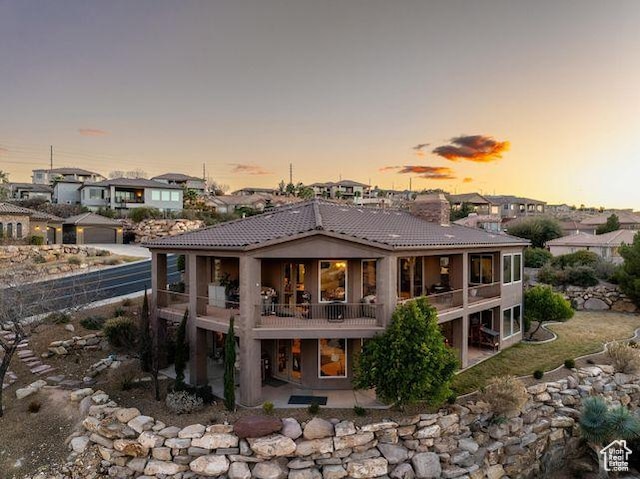 back of property at dusk with a tiled roof, a residential view, and a patio