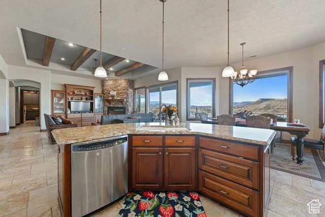 kitchen with open floor plan, hanging light fixtures, stainless steel dishwasher, and a kitchen island