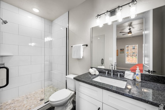 bathroom with a stall shower, ceiling fan, vanity, and toilet