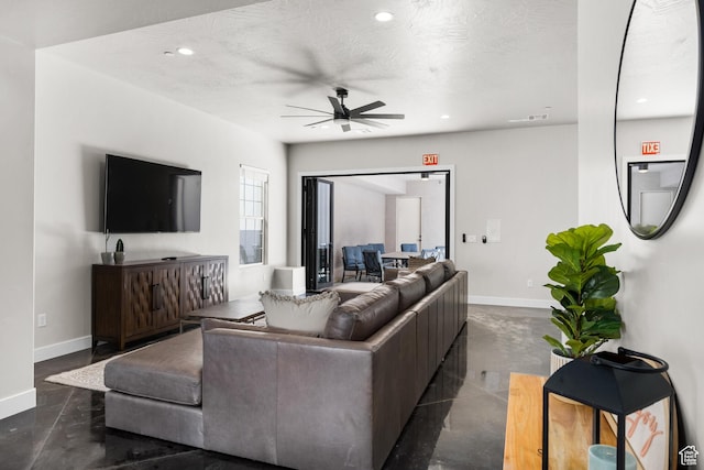 living area with finished concrete floors, baseboards, a textured ceiling, and recessed lighting