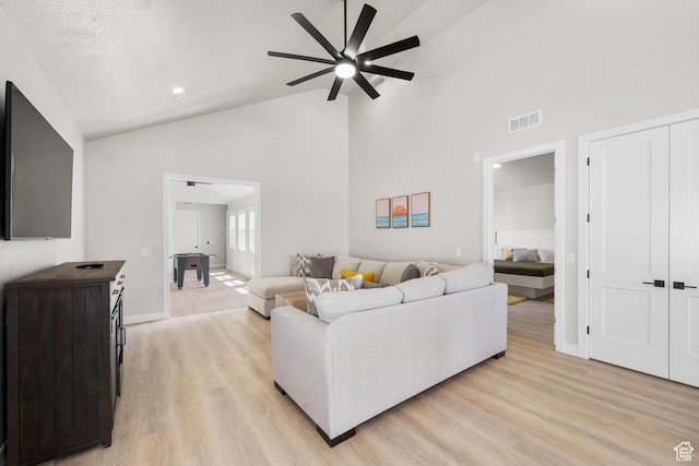 living area featuring high vaulted ceiling, visible vents, baseboards, a ceiling fan, and light wood-type flooring