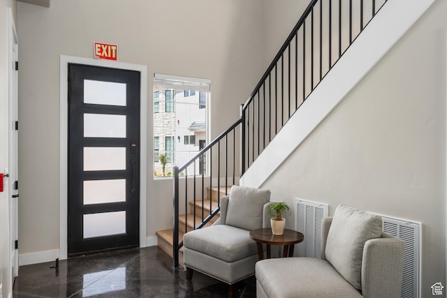 foyer entrance featuring baseboards, visible vents, a high ceiling, stairs, and concrete flooring