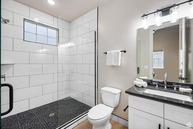 full bathroom featuring vanity, a tile shower, and toilet