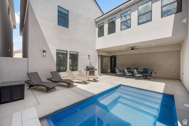 rear view of house with a patio, stucco siding, ceiling fan, an outdoor pool, and a fire pit