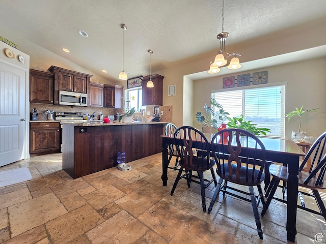 935 W 2100 N, Pleasant View, UT 84404 - kitchen with stainless steel appliances, stone tile flooring, backsplash, dark brown cabinets, and a peninsula