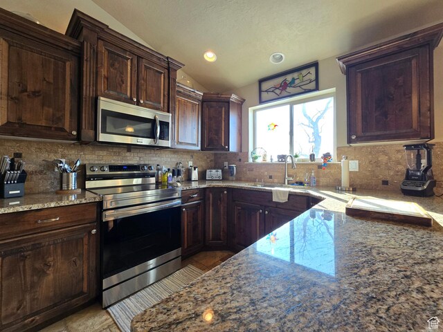 935 W 2100 N, Pleasant View, UT 84404 - kitchen with stainless steel appliances, lofted ceiling, light stone countertops, tasteful backsplash, and a sink