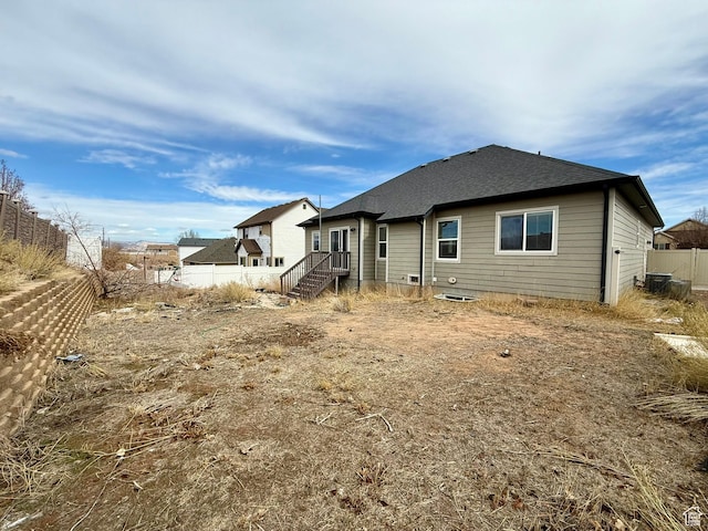 rear view of property with central AC unit, a shingled roof, and fence