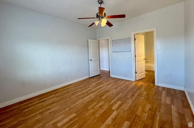 unfurnished bedroom featuring light wood-style flooring, baseboards, ensuite bathroom, and ceiling fan
