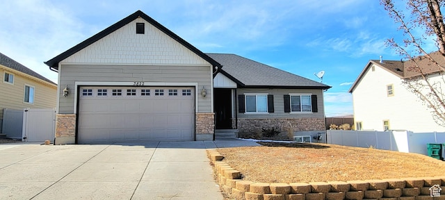 craftsman-style house with stone siding, an attached garage, driveway, and fence