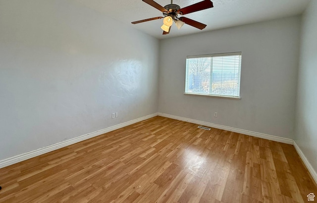 spare room featuring ceiling fan, visible vents, light wood-type flooring, and baseboards