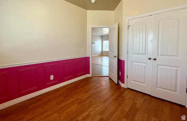 unfurnished bedroom featuring a closet, wainscoting, and wood finished floors
