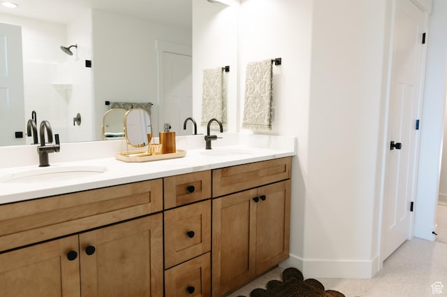 full bath featuring a sink, baseboards, walk in shower, and double vanity