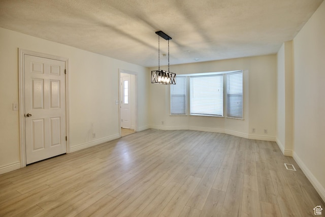 unfurnished room with light wood-type flooring, baseboards, and a chandelier