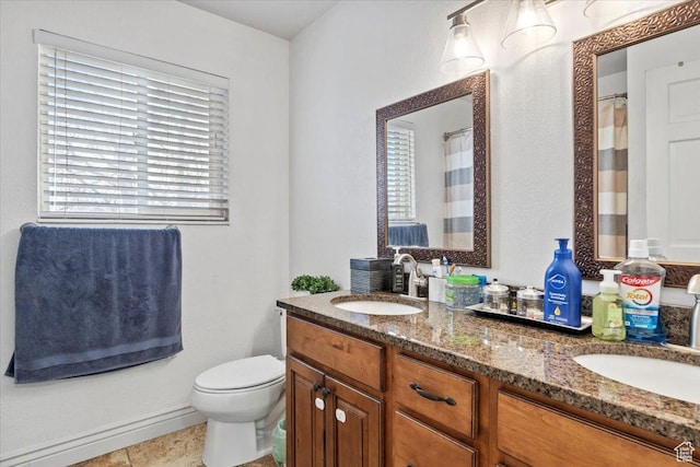 bathroom with plenty of natural light, toilet, double vanity, and baseboards