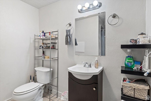 bathroom featuring toilet, vanity, tile patterned flooring, and baseboards