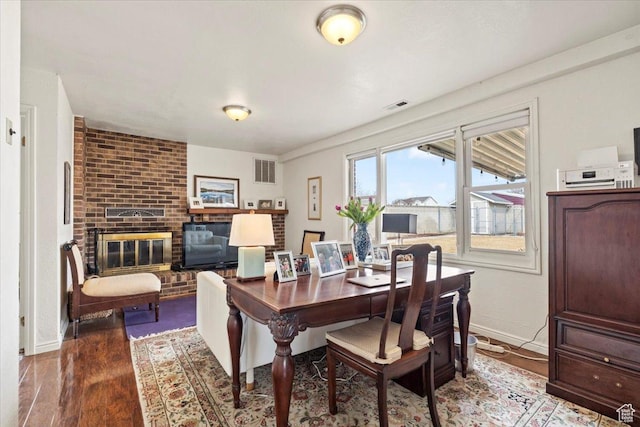 dining area featuring wood finished floors, baseboards, and a fireplace