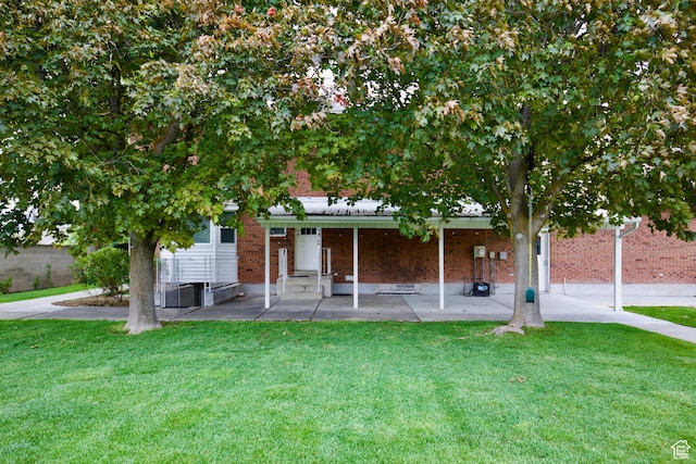 view of front of property featuring brick siding, a patio, and a front lawn