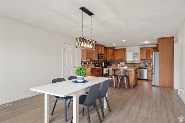 dining room featuring light wood-style flooring, baseboards, and recessed lighting