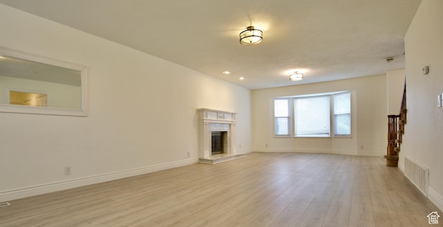 unfurnished living room with a fireplace, light wood finished floors, and baseboards