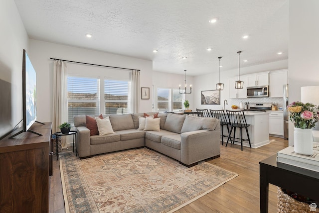 4473 E Hurstbourne Dr, Eagle Mountain, UT 84005 - living room with an inviting chandelier, a textured ceiling, light wood-style floors, and recessed lighting