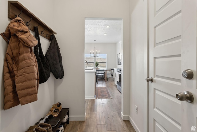 4473 E Hurstbourne Dr, Eagle Mountain, UT 84005 - mudroom featuring baseboards, a textured ceiling, an inviting chandelier, and wood finished floors
