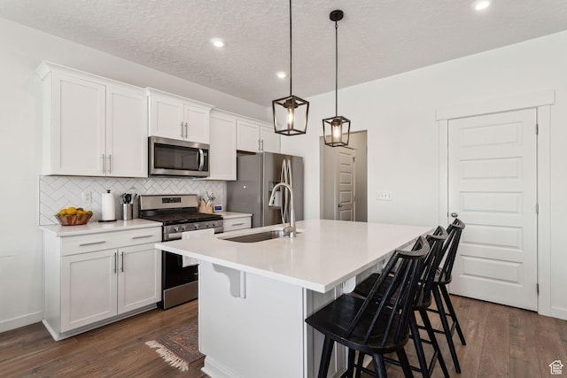 4473 E Hurstbourne Dr, Eagle Mountain, UT 84005 - kitchen featuring pendant lighting, appliances with stainless steel finishes, a kitchen island with sink, and white cabinetry