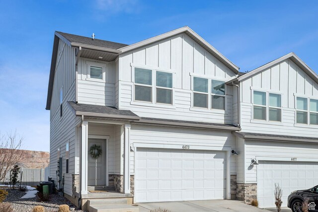townhome / multi-family property featuring driveway, a garage, stone siding, central air condition unit, and board and batten siding