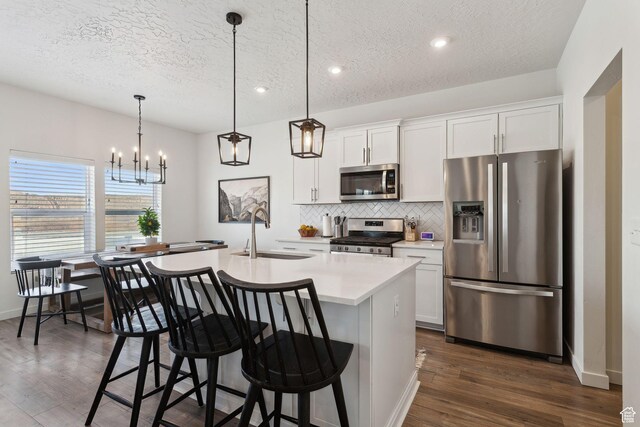 4473 E Hurstbourne Dr, Eagle Mountain, UT 84005 - kitchen featuring decorative light fixtures, light countertops, appliances with stainless steel finishes, white cabinets, and an island with sink