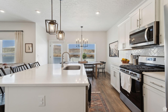 4473 E Hurstbourne Dr, Eagle Mountain, UT 84005 - kitchen featuring a breakfast bar area, stainless steel appliances, hanging light fixtures, light countertops, and a center island with sink