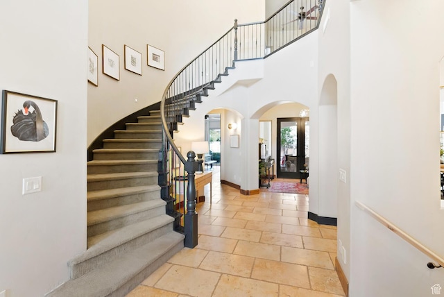802 Leda Ln, Santa Clara, UT 84765 - entrance foyer with arched walkways, a towering ceiling, baseboards, stairway, and stone tile flooring