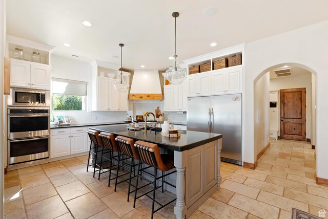 802 Leda Ln, Santa Clara, UT 84765 - kitchen featuring a center island with sink, custom exhaust hood, dark countertops, white cabinets, and built in appliances