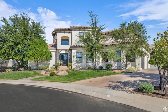 mediterranean / spanish home with decorative driveway, a front yard, a tile roof, and stucco siding