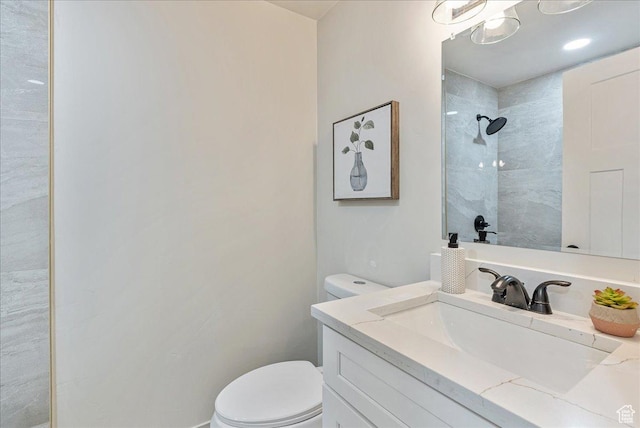 full bath featuring a tile shower, vanity, and toilet
