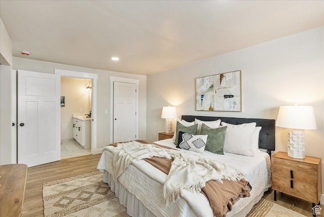 bedroom featuring recessed lighting, baseboards, light wood-style flooring, and ensuite bath