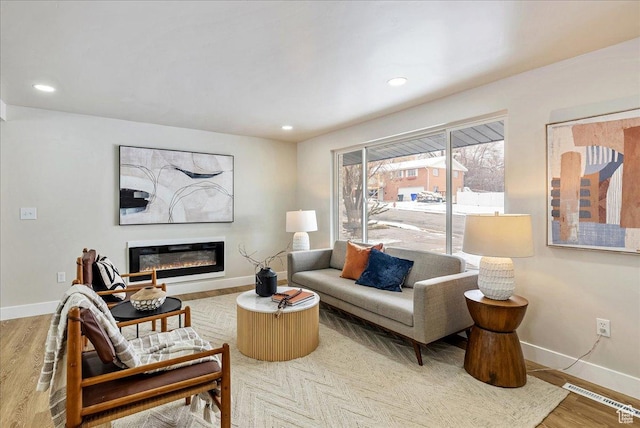 living area with recessed lighting, wood finished floors, visible vents, baseboards, and a glass covered fireplace