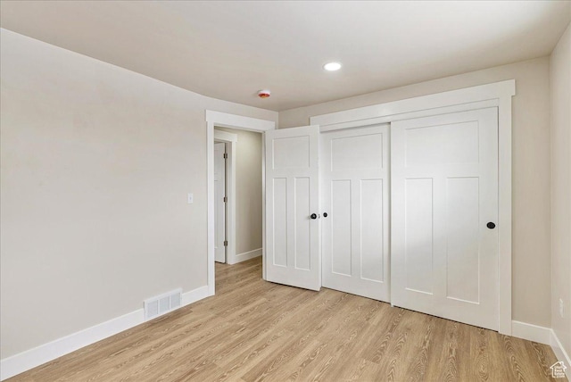 unfurnished bedroom featuring light wood-style flooring, a closet, visible vents, and baseboards