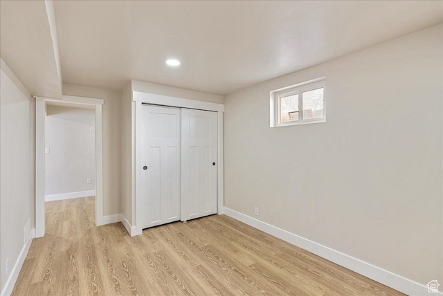 unfurnished bedroom featuring light wood-type flooring, a closet, baseboards, and recessed lighting