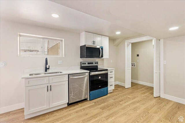 kitchen featuring stainless steel appliances, light countertops, light wood-style floors, white cabinetry, and a sink