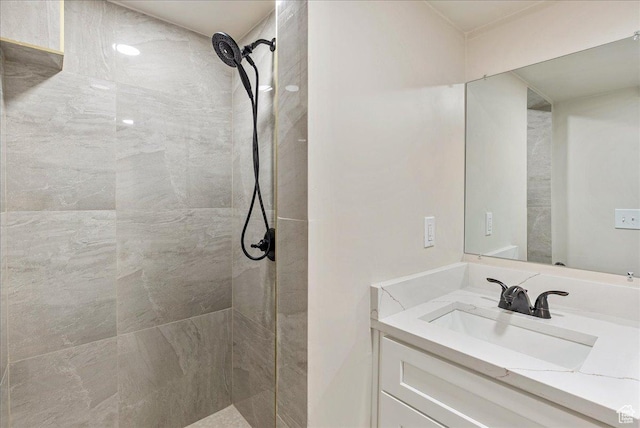bathroom with a tile shower and vanity
