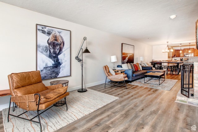 2285 Sidewinder Dr Unit 738, Park City, UT 84060 - living room featuring a textured ceiling, light wood-style flooring, baseboards, and an inviting chandelier